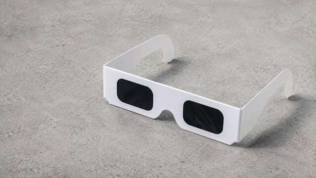 Blank white cardboard protective solar eclipse viewing glasses isolated on a light gray surface