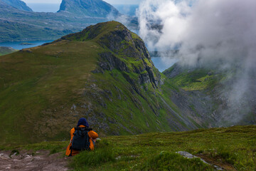 Fototapeta premium Hiker with Orange Backpack Exploring Lofoten Mountains Norway
