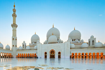 Fototapeta premium Interior courtyard of the white marble Sheikh Zayed Grand Mosque, the largest mosque in the UAE, illuminated at twilight in Abu Dhabi, United Arab Emirates.