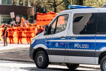 Police car at the edge of a trade union demonstration in Bremen, Germany with protesters in the background  © Ben D.