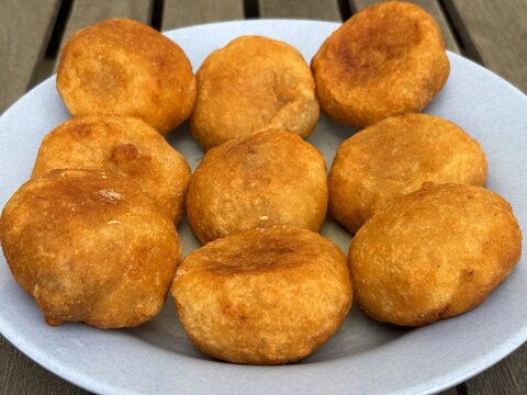 Misro/Jemblem&mdash;a delicious traditional Indonesian snack made of grated cassava with a palm sugar filling, deep-fried until cooked&mdash;is placed on a blue melamine plate.