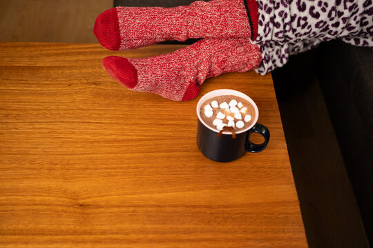 Cozy winter concept with hot chocolate and feet in red socks