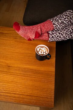 Vertical portrait of a hot chocolate mug on a table with cozy red socks