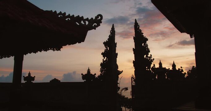 Traditional Balinese architecture silhouettes against purple sunset sky