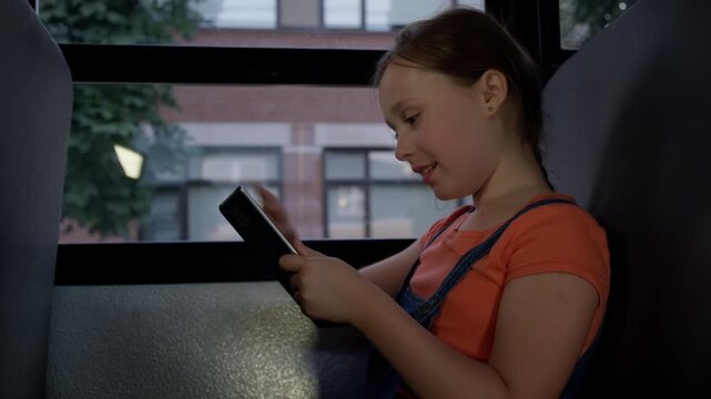 Laughing girl on tablet computer on school bus