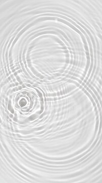Top view of drop falls into water and diverging circles of water in slow motion