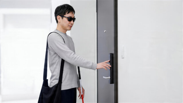 玄関でスマートロックを触って確認する日本人男性