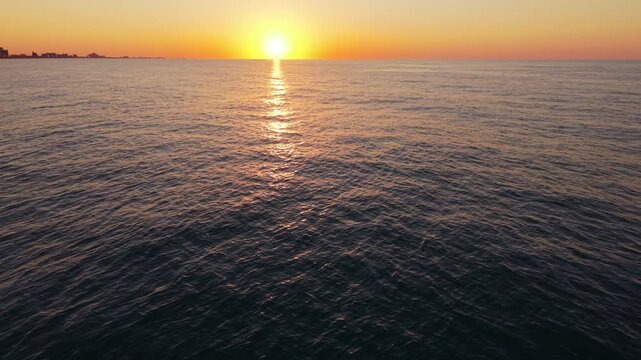 Vibrant sunset casts warm hues over calm ocean waters, reflecting light beautifully, capturing the tranquil atmosphere of Myrtle Beach, South Carolina