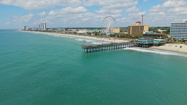 Aerial footage captures Myrtle Beach's lively pier, sandy shoreline, and bustling attractions, highlighting the vibrant coastal atmosphere and clear skies