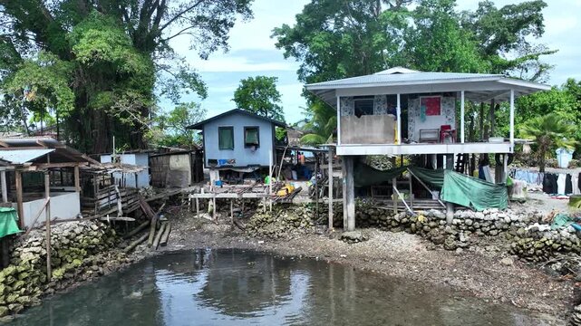 Aerial drone view of traditional stilt houses standing over the water in a remote fishing village on Malaita, Solomon Islands.