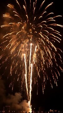 Golden sparks and firework explosions illuminate the night sky during a festive holiday event