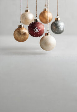 Hanging elegant Christmas ornaments with copy space on light gray background