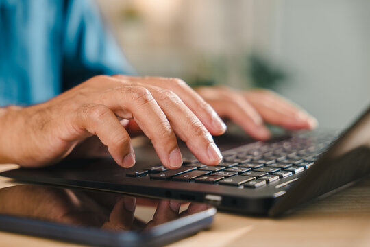 User needs to add credit card financial online payment technology, debit, holding smartphone while typing on laptop keyboard for secure digital banking, shopping, close up of male fingers