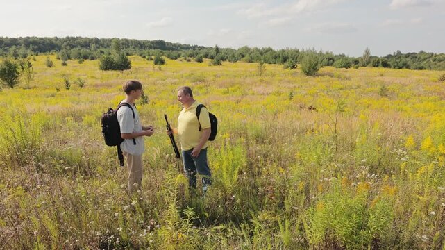 In the background, a lush green forest stretches across the entire horizon under a bright sky.Family bonding during an outdoor adventure in a scenic rural landscape on a sunny day