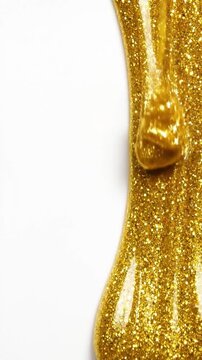 Thick gold glitter glue dripping slowly against a white background for luxury craft concepts