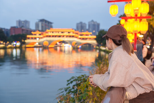 Happy woman traveler travel in Chengdu city. Tourist sightseeing Beautiful Anshun Bridge at night. Famous Landmark for tourism attraction in Sichuan, China