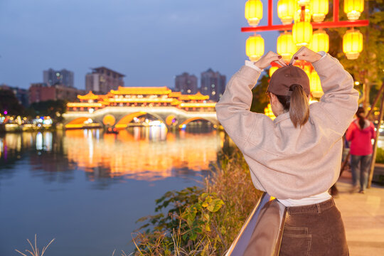 Happy woman traveler travel in Chengdu city. Tourist sightseeing Beautiful Anshun Bridge at night. Famous Landmark for tourism attraction in Sichuan, China