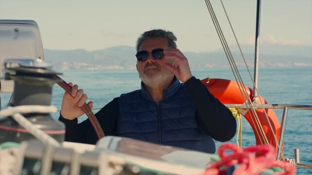 Mature skipper sailing yacht on the ocean