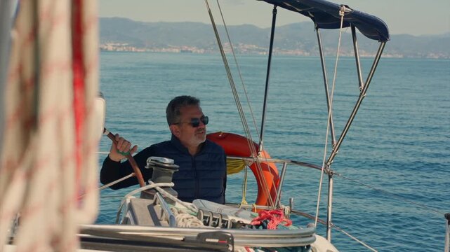 Mature skipper sailing his sailboat on the sea