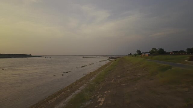 Professional 4K drone footage flying forward along the embankment road beside the Padma River in Kushtia, Bangladesh.