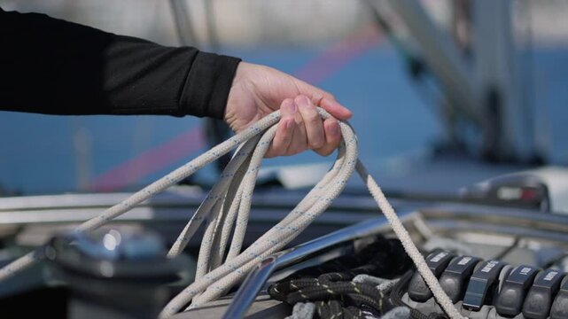Sailor coiling rope on a sailboat deck