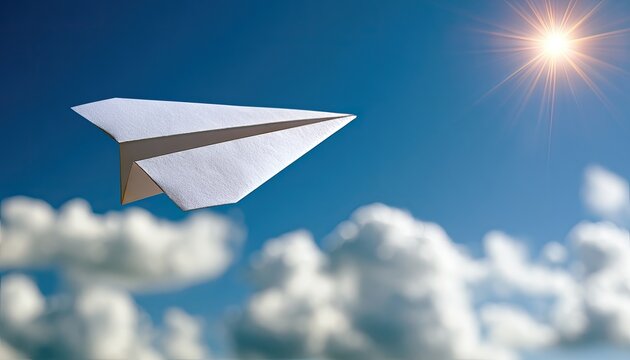A white paper airplane glides through a vibrant blue sky with fluffy clouds and a bright sunburst
