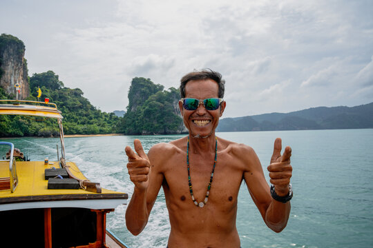 Man smiling and posing on a boat in thailand's tropical sea