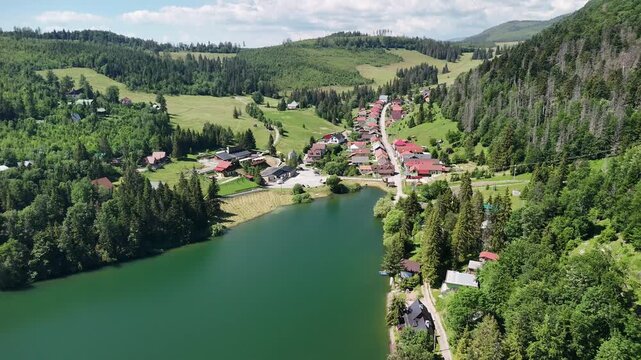 Aerial view of Dobsinska Masa reservoir surrounded by lush green forests and the village of Dedinky, Dedinky, Kosicky kraj, Slovakia.