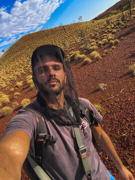 Man wearing mosquito head net hiking in desert outback