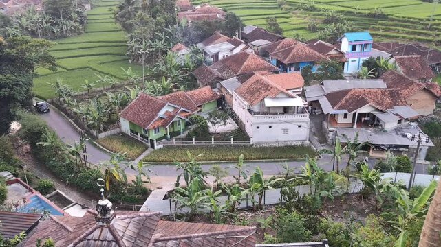 aerial view of a rural settlement with rice fields and light traffic