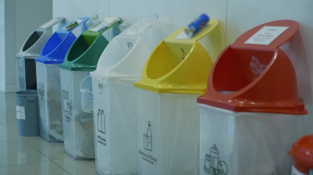 Row of Six Color Coded Recycling Waste Bins Panning Shot