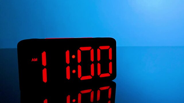 Digital alarm clock changing from 10:59 am to 11:00 am with red led display
