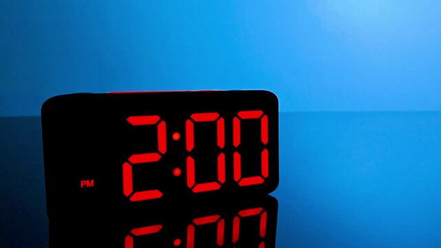 Digital alarm clock changing from 1:59 pm to 2:00 pm with red led display