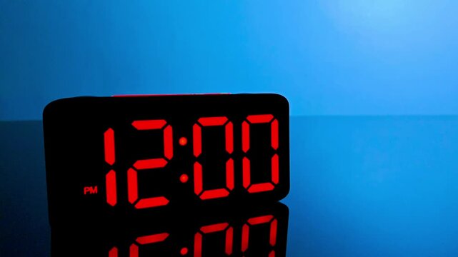 Digital alarm clock changing from 11:59 am to 12:00 pm with red led display