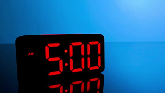 Digital alarm clock changing from 4:59 am to 5:00 am with red led display