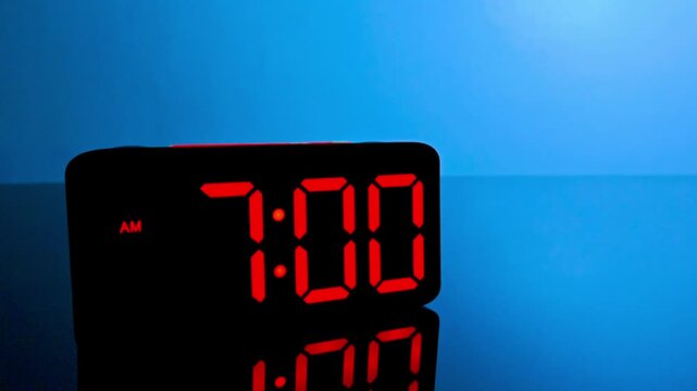 Digital alarm clock changing from 6:59 am to 7:00 am with red led display