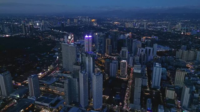 Slow forward drone footage around Twin Oaks building in Shaw Boulevard Mandaluyong Philippines featuring an industrial-commercial setting and the surrounding Metro Manila landscape during blue hour.