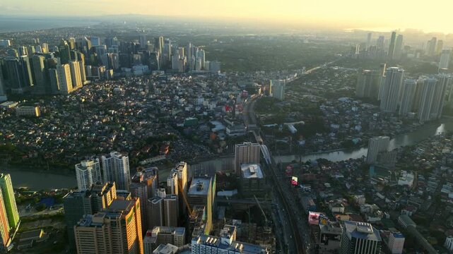 Top view aerial shot of Rockwell and Pasig River in Makati Metro Manila Philippines revealing the bridge, riverbank layout, and clustered high rise buildings at sunset.