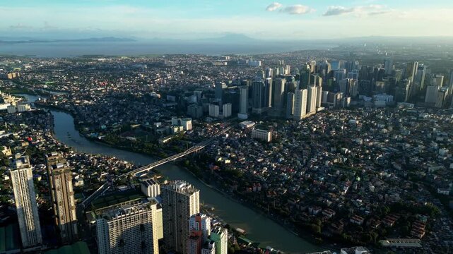 Pullback aerial shot showcasing pasig river, rockwell and high rises building and urban residential around Pasig City Metro Manila Philippines. during daytime.