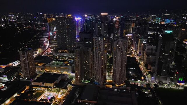 Wide angle aerial shot of Twin Oaks Place and the surrounding Shaw Boulevard area in Mandaluyong Metro Manila Philippines with glowing city lights and dense urban structures.