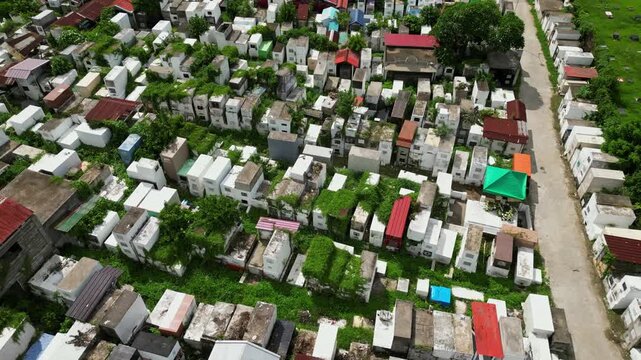 Slow tracking drone shot across Alfonso Public Cemetery highlighting grave plots, mausoleums, open spaces, and nearby roadside areas in Alfonso Cavite.