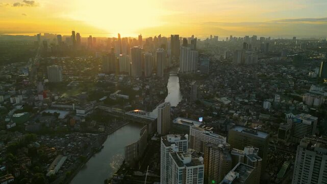 Wide establishing drone footage of Rockwell and Pasig River in Metro Manila Philippines with high rise buildings, illuminated roads, and a calm sunset atmosphere.