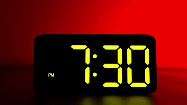  Glowing yellow digital clock changing from 7:29 to 7:30 PM on neon red background