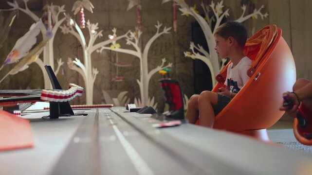 Children playing with tabletop track for cars in creative playroom.