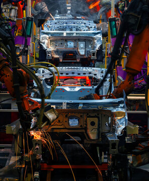 Robotic arms are welding points on the car body on an automated production line.
