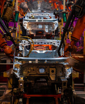 Robotic arms are welding points on the car body on an automated production line.
