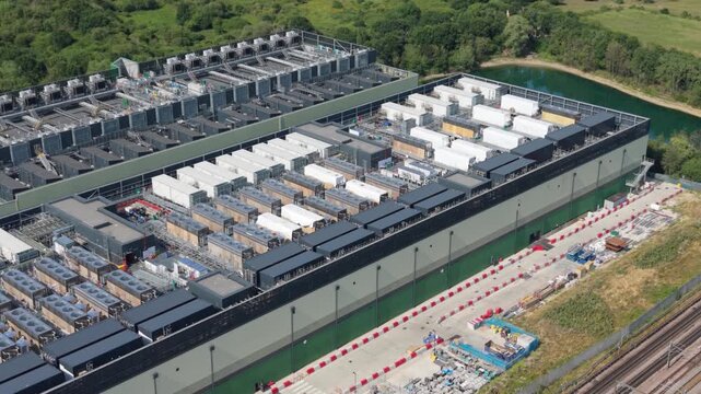 Aerial view of a large data center facility with rows of cooling units and server infrastructure, situated near a pond and green space in London, London, United Kingdom.