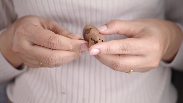 A woman taking the skin off from a tamarind.