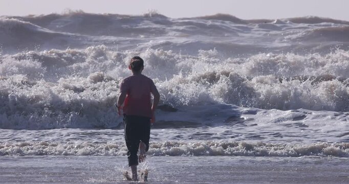 Young Girl Running Toward Large Ocean Waves | Dramatic Telephoto Beach Scene