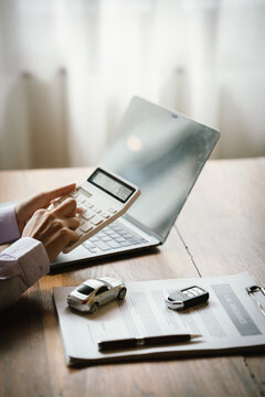 Calculating car insurance costs with a calculator, laptop, and vehicle documents, representing auto finance and insurance planning.